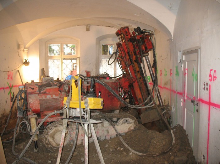 Baumaschinen in einem Raum des Museumsaltbaus, ein riesiger Bohrer bohrt ein Loch in das Erdreich