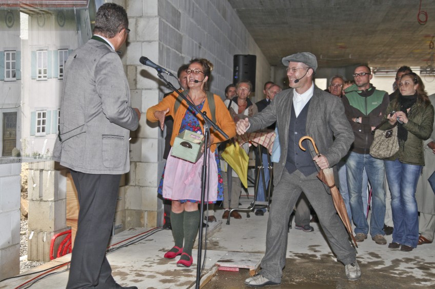 drei Personen spielen ein Theaterstück, im Hintergrund Publikum, im Rohbau des Stadtmuseums