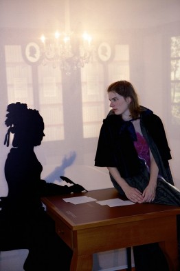 Eine Frau im Umhang sitzt auf dem Schreibtisch mit der Silhouette von Sophie von La Roche.