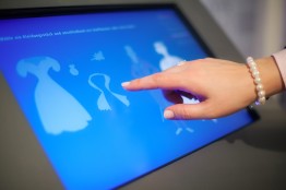 Hand einer Besucherin bedient den Touchscreen im Textilraum des Stadtmuseums Kaufbeuren.