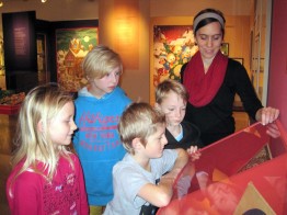 Museumsleiterin Petra Weber zeigt vier Kindern eine Vitrine in der Adventskalender-Ausstellung