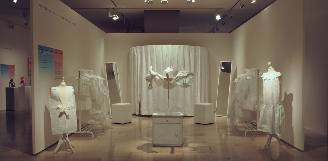 Blick in den Modesalon: mehrere Spiegel und Kleiderpuppen stehen bereit, im Hintergrund ist eine Umkleidekabine