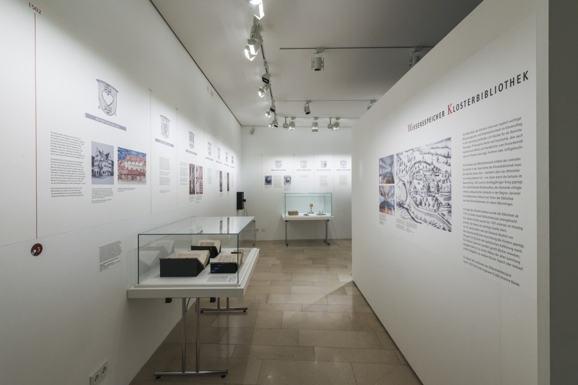 Blick in die Ausstellung: Texte an den Wänden, Glasvitrinen