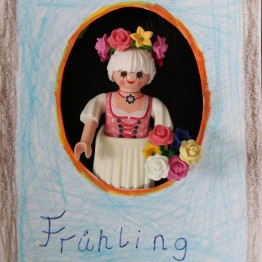 Nachstellung des Hinterglasbildes: Eine Playmobilfrau im Dirndl mit Blumenkranz im Haar und Blumenkorb in der Hand