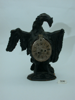 Uhr in Gestalt eines Adlers, der die Flügel ausbreitet. Ziffernblatt auf Brust- und Bauchhöhe