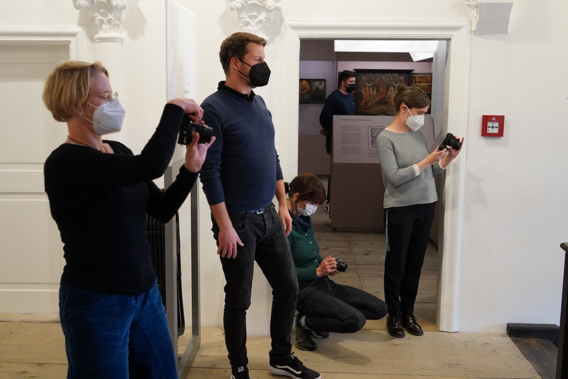 vier Teilnehmer des Technikworkshops, alle mit Maske, im Treppenhaus des Stadtmuseums, drei davon fotografieren mit einer Kamera