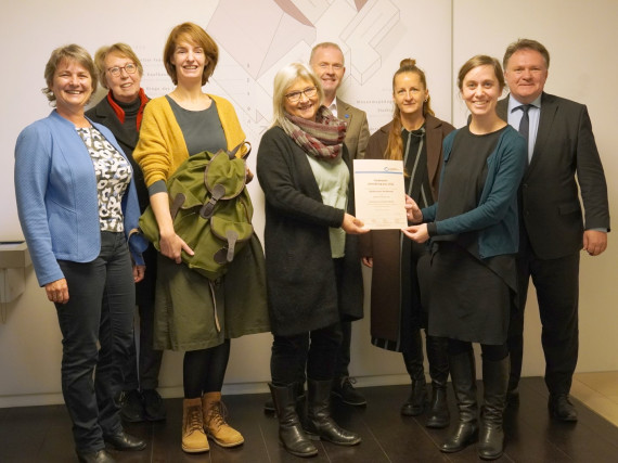 acht Personen im Foyer des Stadtmuseums, Museumsleiterin Petra Weber wird die Urkunde des Förderpreises übergeben