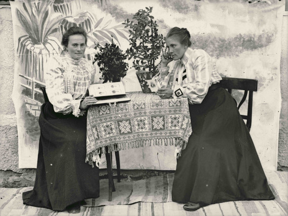 Zwei Frauen an einem Tisch schauen Fotos an.