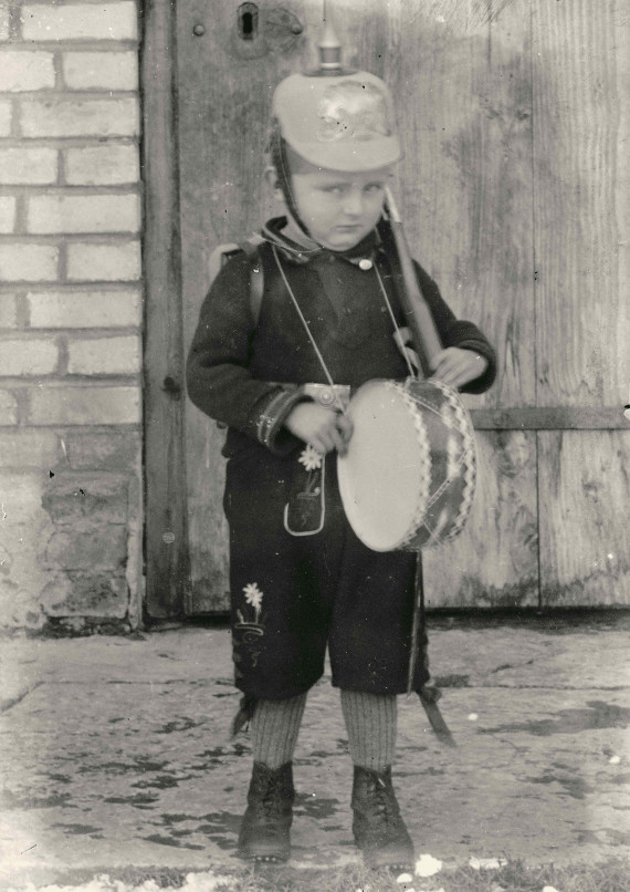 Kleiner Bub mit Pickelhaube und Trommel.