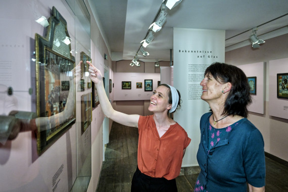 Zwei Frauen betrachten ein Hinterglasbild im Stadtmuseum, eine der beiden Frauen zeigt darauf.